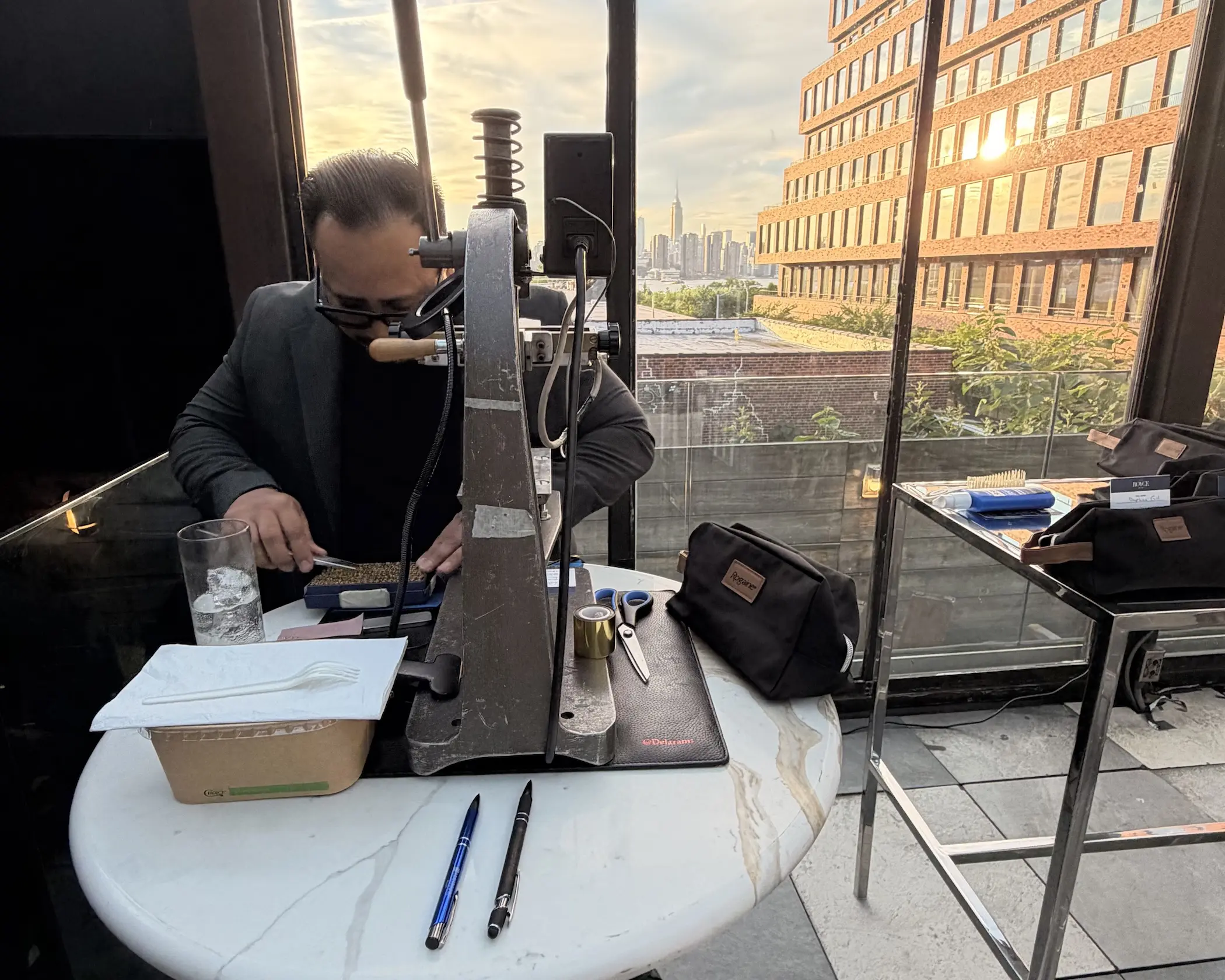 A leather artisan personalizes a Rogaine dopp kit at a customization station overlooking the New York skyline.