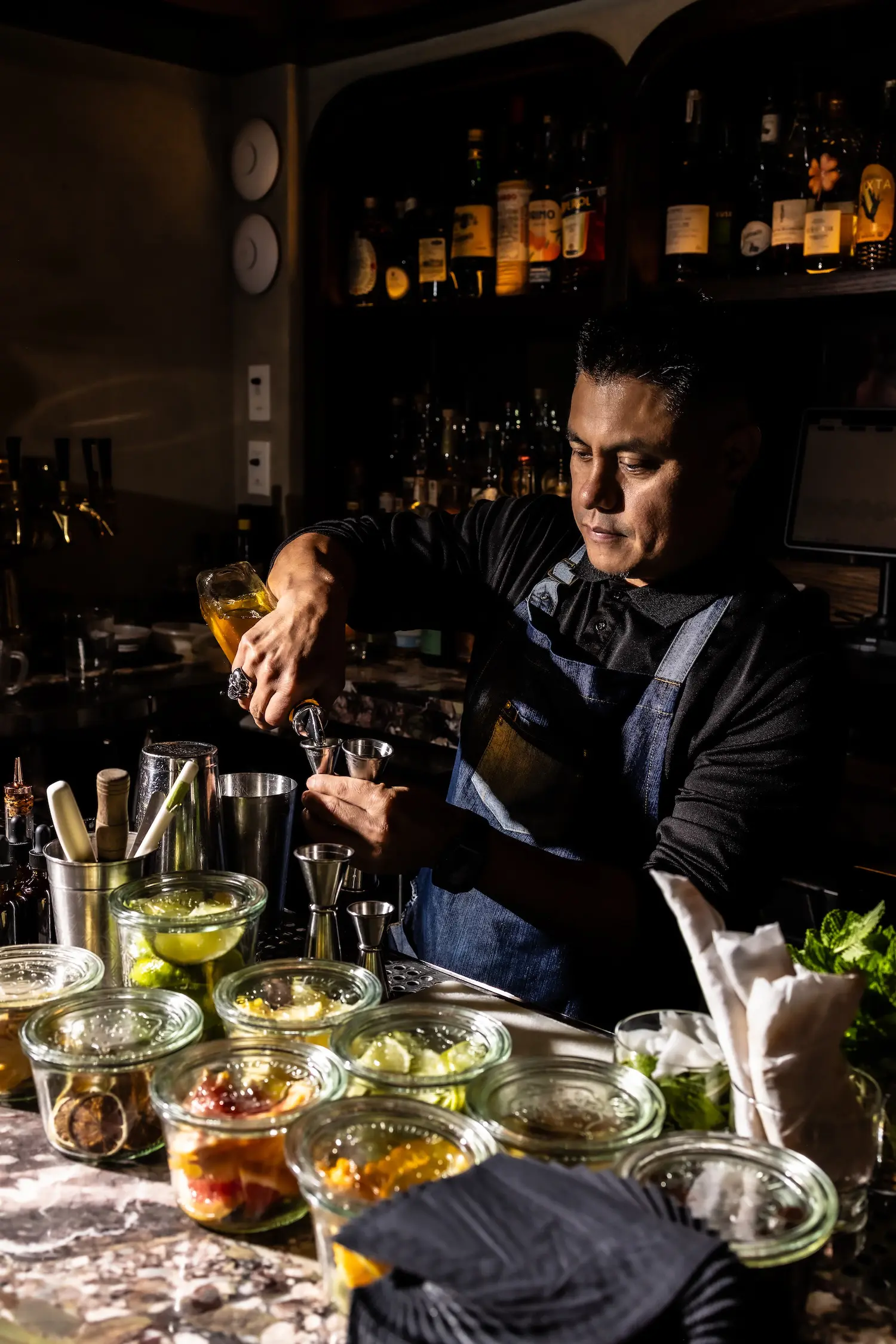 LOLITA Beverage Director Marshall Minaya measures spirits behind the bar while preparing cocktails for the Corazón Cabo chef collaboration.