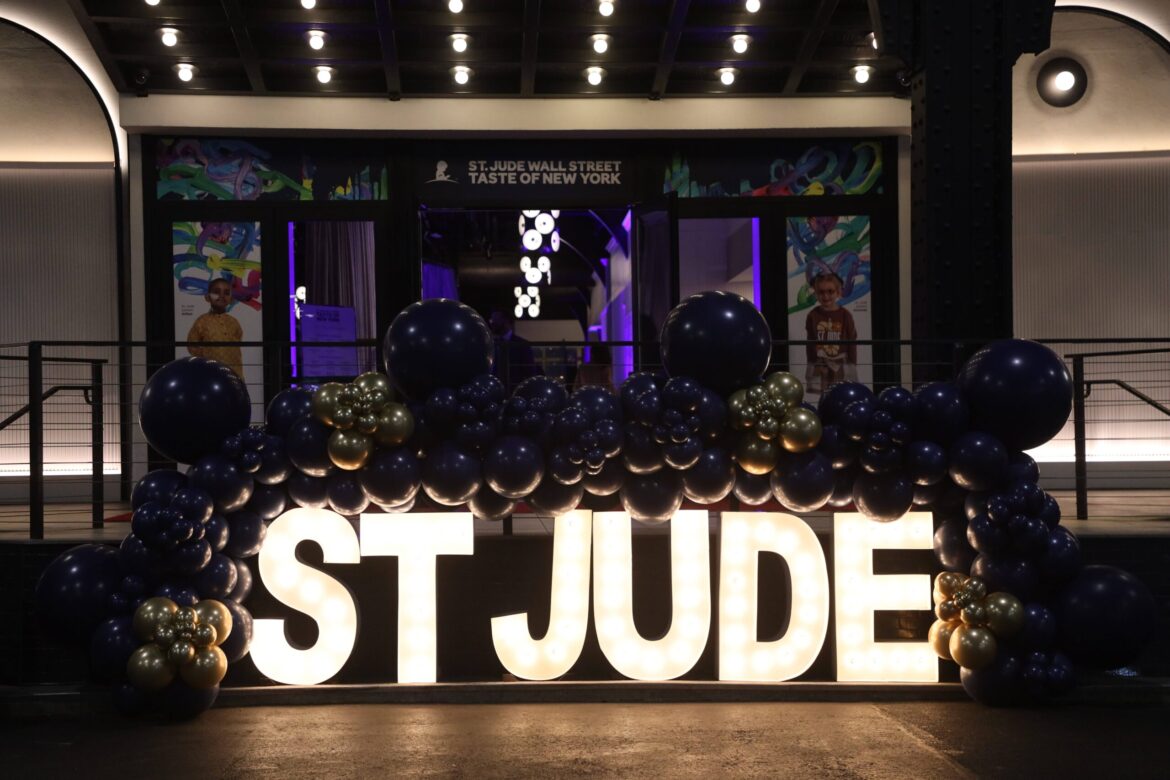 Illuminated St. Jude sign decorated with navy and gold balloons at the entrance of the St. Jude Taste of New York Gala.