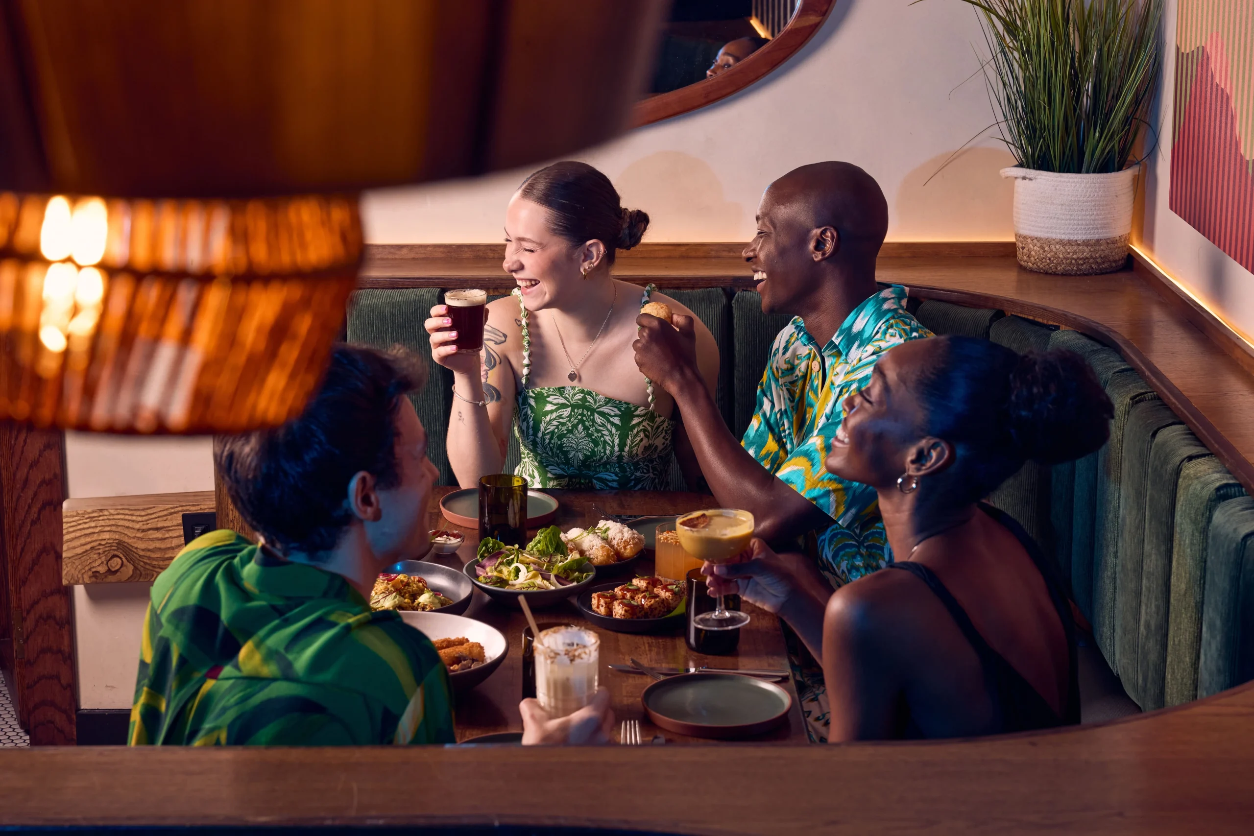 People laughing and enjoying themselves at Berimbau. Drinking cocktails and eating good food in a vibrant environment.