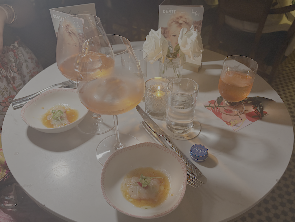 Cocktails and crudo dishes displayed on a candlelit table during the LPM Restaurant & Bar and Dante event